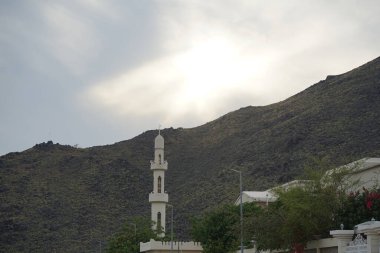 IMAM MALIK MOSQUE minaresi Nisan ayında Khor Fakkan şehrinde günbatımının arka planında görülmektedir. Minare, genellikle camilerin içine veya yakınına inşa edilmiş bir kule türüdür. Şeriat, Birleşik Arap Emirlikleri.                              