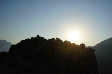 Nisan 2023 'te yeniden inşa edilmeden önce, Khor Fakkan, Sharjah, BAE' deki Al Suwaifa Yürüyüş Patikası 'nın yakınındaki günbatımına karşı gözlem kulesinin yıkıntılarıyla birlikte dağın manzarası.. 