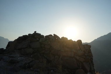 Nisan 2023 'te yeniden inşa edilmeden önce, Khor Fakkan, Sharjah, BAE' deki Al Suwaifa Yürüyüş Patikası 'nın yakınındaki günbatımına karşı gözlem kulesinin yıkıntılarıyla birlikte dağın manzarası.. 