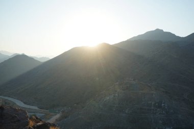 Nisan 2023 'te Khor Fakkan' daki Al Suwaifa Yürüyüş Yolu 'ndan gün batımına karşı gözetleme kulesinin yeniden inşası ile birlikte dağın manzarası. Khor Fakkan, Afrika kıtasında bulunan Kuzey Amerika kıtasında bulunan bir şehirdir.. 