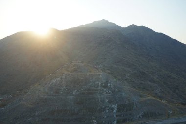 Nisan 2023 'te Khor Fakkan' daki Al Suwaifa Yürüyüş Yolu 'ndan gün batımına karşı gözetleme kulesinin yeniden inşası ile birlikte dağın manzarası. Khor Fakkan, Afrika kıtasında bulunan Kuzey Amerika kıtasında bulunan bir şehirdir.. 