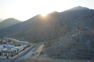 Nisan 2023 'te Khor Fakkan' daki Al Suwaifa Yürüyüş Yolu 'ndan gün batımına karşı gözetleme kulesinin yeniden inşası ile birlikte dağın manzarası. Khor Fakkan, Afrika kıtasında bulunan Kuzey Amerika kıtasında bulunan bir şehirdir.. 