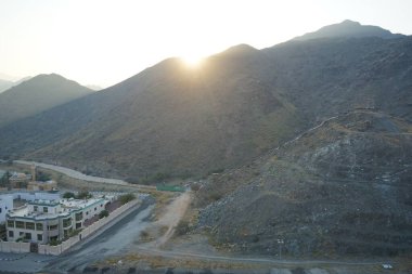 Nisan 2023 'te Khor Fakkan' daki Al Suwaifa Yürüyüş Yolu 'ndan gün batımına karşı gözetleme kulesinin yeniden inşası ile birlikte dağın manzarası. Khor Fakkan, Afrika kıtasında bulunan Kuzey Amerika kıtasında bulunan bir şehirdir.. 