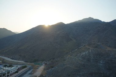 Nisan 2023 'te Khor Fakkan' daki Al Suwaifa Yürüyüş Yolu 'ndan gün batımına karşı gözetleme kulesinin yeniden inşası ile birlikte dağın manzarası. Khor Fakkan, Afrika kıtasında bulunan Kuzey Amerika kıtasında bulunan bir şehirdir.. 