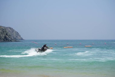 Khor Fakkan, Sharjah, BAE - 21 Nisan 2023: Turistler Khor Fakkan Sahili boyunca Umman Körfezi 'nde su motosikletine biniyorlar. Kişisel su aracı, PWC, su motoru, jet ski, bir su gemisidir..                                