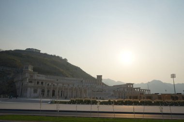 Khor Fakkan, Sharjah, BAE - 24 Nisan 2023: Güneş Nisan akşamı Hurfakkan Amfitiyatrosunun üzerinde parlıyor. Hurfakkan Amfitiyatrosu, Khor Fakkan 'da bulunan Şeriat Emirliği' nin açık hava tiyatrosu ve kültürel simgesidir.. 