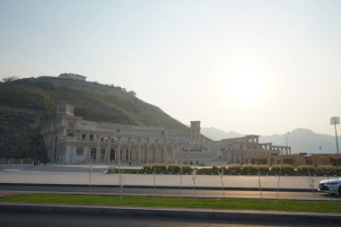 Khor Fakkan, Sharjah, BAE - 24 Nisan 2023: Güneş Nisan akşamı Hurfakkan Amfitiyatrosunun üzerinde parlıyor. Hurfakkan Amfitiyatrosu, Khor Fakkan 'da bulunan Şeriat Emirliği' nin açık hava tiyatrosu ve kültürel simgesidir.. 