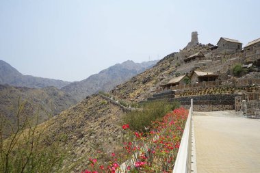 Nisan ayında gözlem kulesi ve eski Najd Al Miqsar köyü ile kalenin manzarası. Najd Al Miqsar, Khor Fakkan 'ın batısında, BAE' nin başkenti Sharjah 'ta terk edilmiş tarihi bir yerleşim yeridir.. 