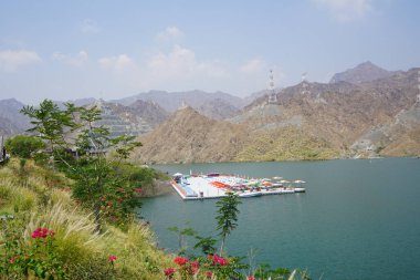 Al-Bid 'ah rezervuarı ve Al-Rafisah Barajı' ndaki Nisan ayındaki bitki örtüsü ile pitoresk bir sahilden Al-Khor Kayık tekne istasyonu manzarası. Wadi Wshee, Sharjah, BAE. 