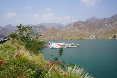 Al-Bid 'ah rezervuarı ve Al-Rafisah Barajı' ndaki Nisan ayındaki bitki örtüsü ile pitoresk bir sahilden Al-Khor Kayık tekne istasyonu manzarası. Wadi Wshee, Sharjah, BAE. 