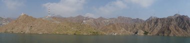 Fotoğraf panoraması. Nisan ayında El Rafisah Barajı 'nın dinlenme alanından dağlarla ve bitki örtüsüyle çevrili güzel Hawd al Bid' ah rezervuarının manzarası. Wadi Wshee, Sharjah, BAE. 