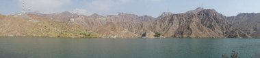 Fotoğraf panoraması. Nisan ayında El Rafisah Barajı 'nın dinlenme alanından dağlarla ve bitki örtüsüyle çevrili güzel Hawd al Bid' ah rezervuarının manzarası. Wadi Wshee, Sharjah, BAE. 