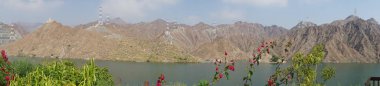 Fotoğraf panoraması. Nisan ayında El Rafisah Barajı 'nın dinlenme alanından dağlarla ve bitki örtüsüyle çevrili güzel Hawd al Bid' ah rezervuarının manzarası. Wadi Wshee, Sharjah, BAE. 