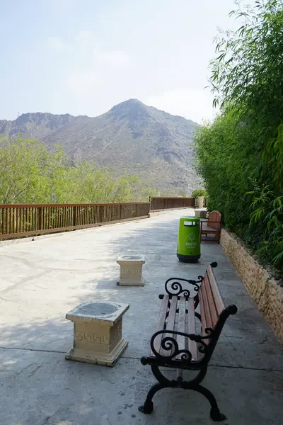 Tahta banklar ve saksılardaki çiçekler, Hawd al Bid 'ah rezervuarının yakınındaki Al Rafisah Barajı dinlenme alanında. Wadi Wshee, Sharjah, BAE.