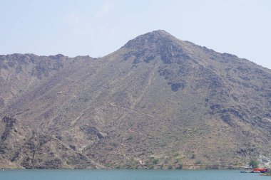 Hawd al Bid 'ah rezervuarının ve Nisan ayında El Rafisah Barajı' ndan çevresini çevreleyen dağların manzarası. Wadi Wshee, Sharjah, BAE.