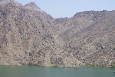 El Rafisah Barajı dinlenme alanında Hawd al Bid 'ah rezervuarı boyunca şişme motorlu tekne yüzüyor. Wadi Wshee, Sharjah, BAE.           