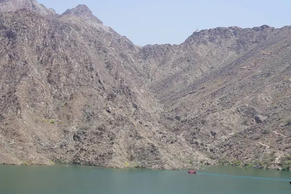 El Rafisah Barajı dinlenme alanında Hawd al Bid 'ah rezervuarı boyunca şişme motorlu tekne yüzüyor. Wadi Wshee, Sharjah, BAE.           