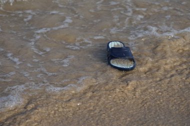 Khor Fakkan, Sharjah, Birleşik Arap Emirlikleri 'ndeki Umman Körfezi' nde kadınlar için kauçuk plaj terliği deniz suyunun kenarında yatıyor.. 