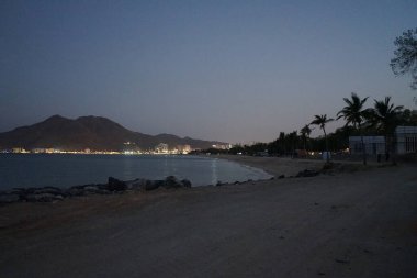 Nisan akşamı Umman Körfezi manzarası ve Khor Fakkan kenti kıyısı. Khor Fakkan, Birleşik Arap Emirlikleri 'nin doğu kıyısında, Şeriat Emirliği' ne bağlı bir şehirdir..                 