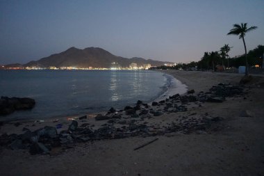 Nisan akşamı Umman Körfezi manzarası ve Khor Fakkan kenti kıyısı. Khor Fakkan, Birleşik Arap Emirlikleri 'nin doğu kıyısında, Şeriat Emirliği' ne bağlı bir şehirdir..                 
