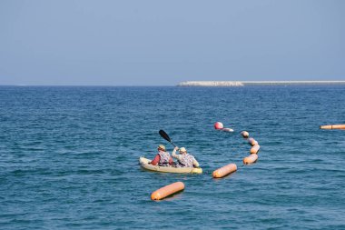 Khor Fakkan, Sharjah, BAE - 27 Nisan 2023: Nisan 'da Khor Fakkan Sahili yakınlarındaki Umman Körfezi' nde iki turist sarı bir kano ile kürek çekiyor.                           