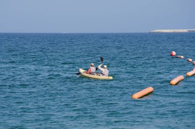 Khor Fakkan, Sharjah, BAE - 27 Nisan 2023: Nisan 'da Khor Fakkan Sahili yakınlarındaki Umman Körfezi' nde iki turist sarı bir kano ile kürek çekiyor.                           
