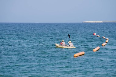 Khor Fakkan, Sharjah, BAE - 27 Nisan 2023: Nisan 'da Khor Fakkan Sahili yakınlarındaki Umman Körfezi' nde iki turist sarı bir kano ile kürek çekiyor.                           