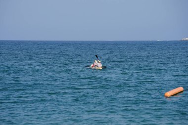 Khor Fakkan, Sharjah, BAE - 27 Nisan 2023: Nisan 'da Khor Fakkan Sahili yakınlarındaki Umman Körfezi' nde iki turist sarı bir kano ile kürek çekiyor.                           