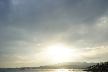 Güneş, İspanya 'nın Mallorca adasındaki Palma şehrindeki Akdeniz kıyısında bulutların arasından yükselir..                                   