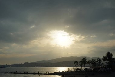 Güneş, İspanya 'nın Mallorca adasındaki Palma şehrindeki Akdeniz kıyısında bulutların arasından yükselir..                                   