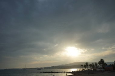 Güneş, İspanya 'nın Mallorca adasındaki Palma şehrindeki Akdeniz kıyısında bulutların arasından yükselir..                                   