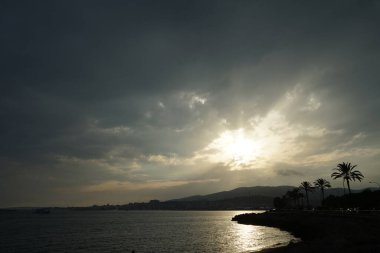 Güneş, İspanya 'nın Mallorca adasındaki Palma şehrindeki Akdeniz kıyısında bulutların arasından yükselir..                                   