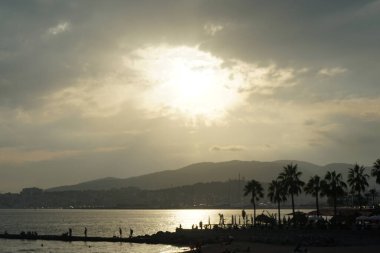 Güneş, İspanya 'nın Mallorca adasındaki Palma şehrindeki Akdeniz kıyısında bulutların arasından yükselir..                                