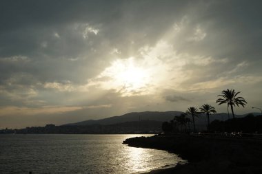 Güneş, İspanya 'nın Mallorca adasındaki Palma şehrindeki Akdeniz kıyısında bulutların arasından yükselir..                                