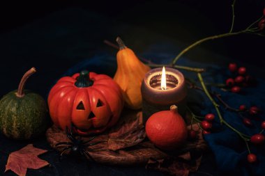 Cadılar Bayramı şenlik düzeni Jack-O-Lantern, balkabakları, mum ve örümceklerle siyah masada tahta kesme tahtasında. Sonbahar tatili konsepti. Yakın çekim..