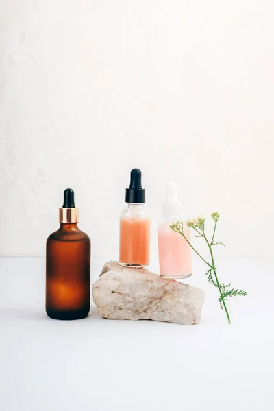 stock image Brown cosmetic oil and serum bottles and yarrow flower on white background. Natural cosmetics, spa and wellness concept.