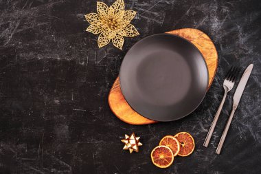 Kesme tahtası, çatal, bıçak, Noel süslemeleri ve portakal dilimli siyah masa. Üst görünüm, düz görünüm, kopyalama alanı.