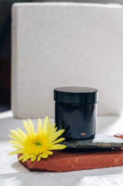 Siyah krema kavanozu ve sarı çiçek. Cilt bakımı, kaplıca ve sağlık konsepti. Yakın çekim..