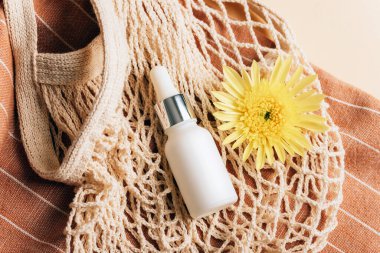 Sarı kasımpatı çiçekli beyaz kozmetik serumu şişesi. Organik kaplıca güzellik ürünü. Sıfır atık.