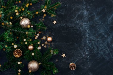 Noel ağacı dalları, altın takılar ve siyah arka planda Noel ışıkları olan çam kozalakları. Yeni yıl konsepti. Üst görünüm, alanı kopyala.