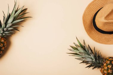 Tarafsız bej arka planda kadın yaz aksesuarları, şapka ve ananas. Güzellik, moda, yaz tatili konsepti. Üst görünüm, düz görünüm, kopyalama alanı.