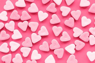 Pembe şeker şekerler, canlı mor arkaplanda kalp şeklinde. Yaratıcı tatil aşkı kavramı. Sevgililer Günü.