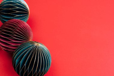 Kırmızı arka planda süslemeli kağıt Noel ağacı takıları. Üst görünüm, alanı kopyala.