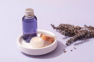 Beyaz tepside lavanta yağı ve krema ve kurutulmuş lavanta çiçeği. Cilt bakımı, aromaterapi, kişisel bakım konsepti. Yakın çekim..