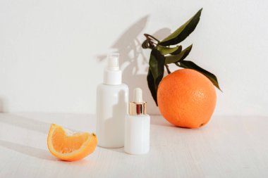 Cosmetic serum bottles and orange fruits on white background. Natural cosmetics concept, mockup.