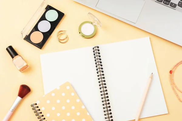 stock image Blank notepad, makeup cosmetics and laptop computer on beige background, top view. Creative flat lay, mockup.