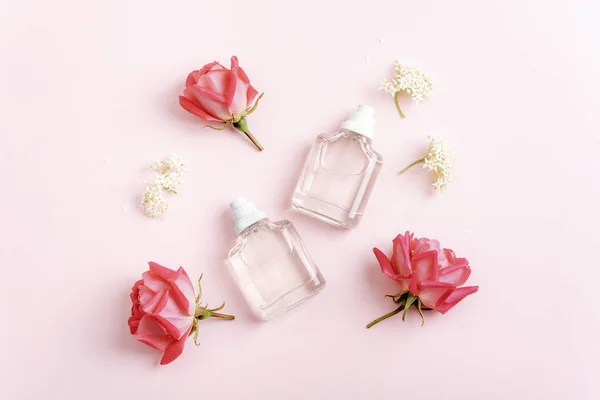 stock image Two perfume bottles and rose flowers on pink background. Beauty, fashion concept. Top view, flat lay, mockup.