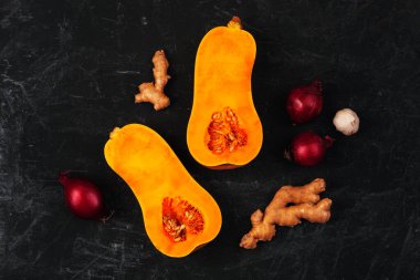 Kırmızı soğanlı çiğ tereyağlı ezme, zencefil ve sarımsaklı siyah arka plan. Balkabağı çorbası malzemeleri. Üst manzara, düz uzanma.