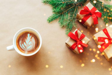 Noel ve Yeni Yıl tatili geçmişi. Noel ağacı dalları, kırmızı fiyonklu hediye kutuları, el işi kağıdının üzerinde bir fincan kahve. Üst manzara, düz uzanma.