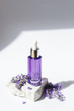 Lavanta kozmetik serumu şişesi gün ışığında taş podyumda. Doğal kozmetik, aromaterapi konsepti. Yakın plan..